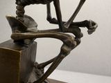 a bronze sculpture of a skeleton sitting on a box