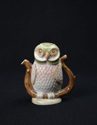 une figurine de chouette perchée sur une branche d'arbre
