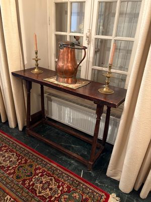 une table sur laquelle est posé un vase, devant une fenêtre