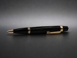 un stylo à bille noir et doré posé sur une surface noire