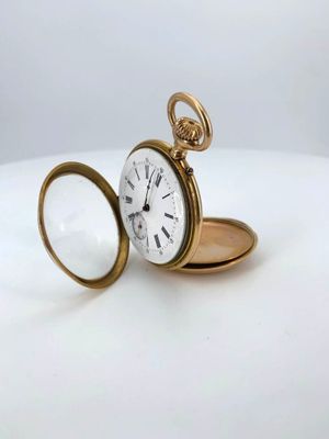 an antique pocket watch with a magnifying glass on a white surface