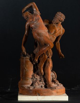 une statue représentant un homme tenant une femme dans ses bras, posée sur un socle en bois
