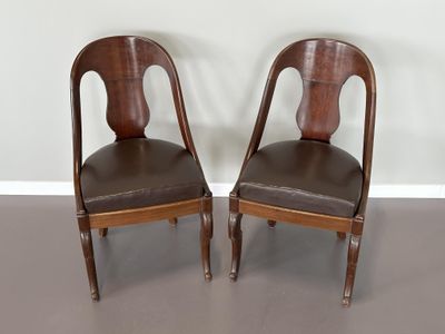 deux chaises en bois avec des assises rembourrées de cuir dans une pièce