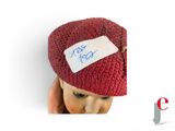 a small child wearing a knitted hat with a note on it