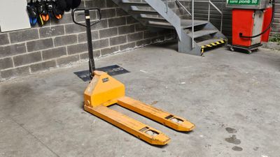 un chariot élévateur jaune garé devant un bâtiment