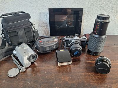 une table avec un appareil photo, un étui pour appareil photo, un objectif, un étui pour appareil photo, un étui pour appareil photo et un sac pour appareil photo