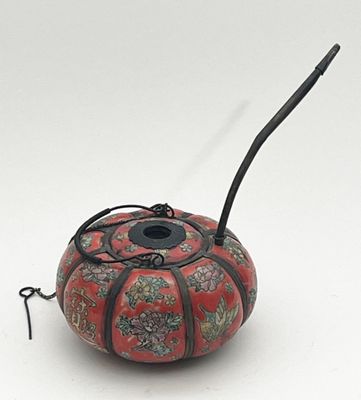 a red and black vase with a black handle on a white surface