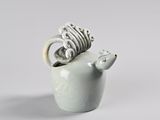a small ceramic animal with a ring in it ' s mouth