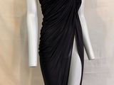 Le mannequin porte une robe noire à jupe drapée.