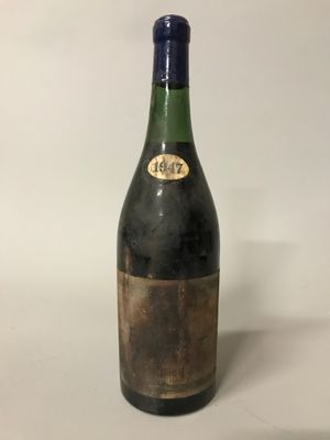 une vieille bouteille de vin posée sur une table blanche