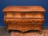 an antique chest of drawers on a rug in front of a blue wall