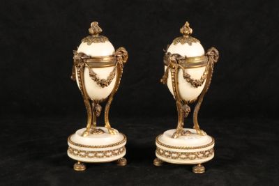 two white and gold vases sitting on top of a black surface