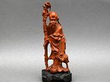 une ancienne figurine chinoise sculptée représentant un homme tenant un bâton