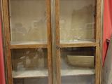 a wooden cabinet with glass doors and a red curtain in the background