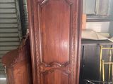 une armoire en bois posée à côté d'une chaise dans une pièce