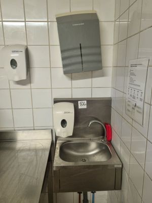 a sink in a public restroom with a paper towel dispenser