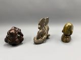 three bronze figurines of animals on a white surface
