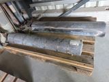 un tas de tuyaux métalliques posés sur une palette dans un entrepôt