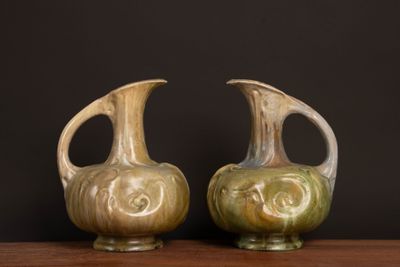 two vases sitting on a table with a black background