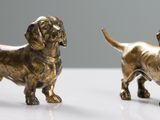 paire de figurines de teckels dorés sur un fond blanc