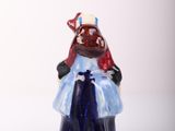 a small figurine of a woman wearing a blue dress and a red hat