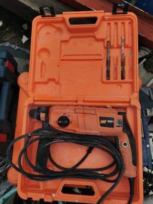 une boîte à outils orange contenant des outils, posée par terre