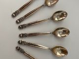 six silver spoons are arranged in a circle on a white surface