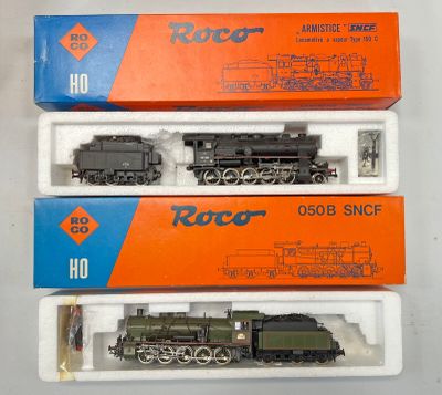 trois trains miniatures dans leurs boîtes, empilés les uns sur les autres sur une table