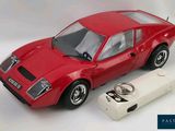 a red toy car next to a keychain on a white background