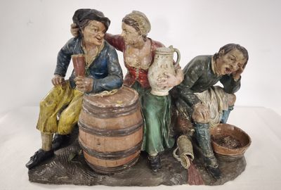 a figurine of three people sitting on a barrel