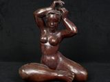 a bronze statue of a woman sitting on a black background