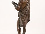 bronze statue of a man reading a book on a wooden base