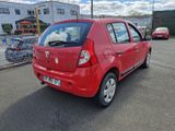 une voiture rouge garée sur un parking près d'une clôture