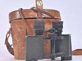 a brown bag and a pair of binoculars on a white surface