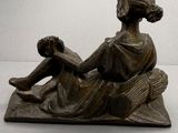 statue en bronze représentant une femme assise sur un rocher avec un enfant