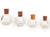 trois petites bouteilles en verre avec des couvercles en bois, posées sur une surface blanche