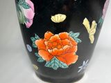a black vase with flowers and butterflies painted on it