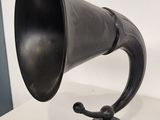 an old fashioned black horn on a wooden stand