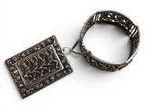an antique silver bracelet with a square pendant and a chain on a white background