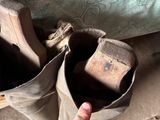 a hand pointing at a pair of shoes on the ground