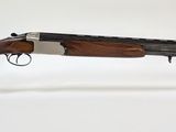 Le fusil est exposé sur un socle en acrylique transparent.