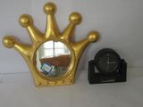 un miroir en forme de couronne dorée et une horloge posés sur une table