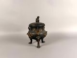 a small bronze incense pot with a lid on a white background