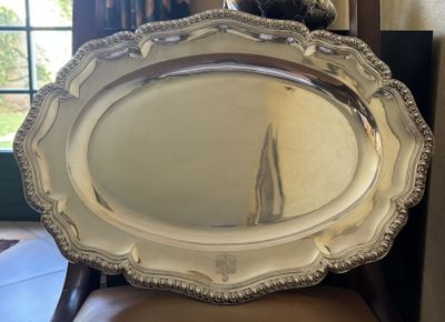 a large silver platter sitting on a chair in front of a window