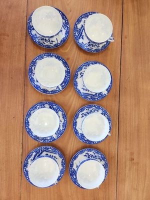 six blue and white china cups and saucers on a wooden table
