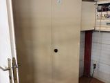 a metal cabinet in the corner of a room with a door open