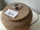 a cork covered jar with a metal handle on a table