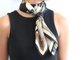 a woman wearing a black tank top with a scarf around her neck