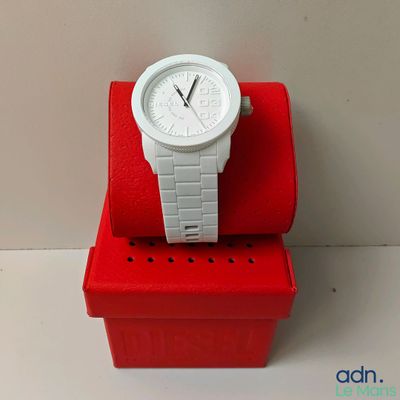 une montre blanche posée sur une boîte rouge