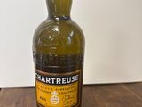 the bottle of chartreuse is sitting on a wooden table